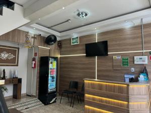 a lobby with a bar with a tv on the wall at Pousada Rabake in Aparecida