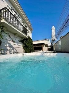 a swimming pool in front of a house with an umbrella at Pousada Villa D Manu in Penha