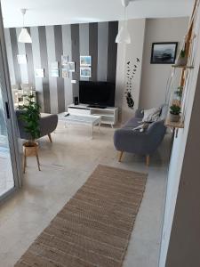 uma sala de estar com duas cadeiras e uma televisão em Fantástico apartamento playa em Cala de Finestrat