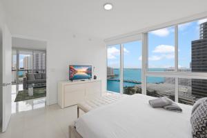 a white bedroom with a view of the ocean at 2B2B w Water View - FREE Parking - Pool - Lux Spa in Miami +32 photos