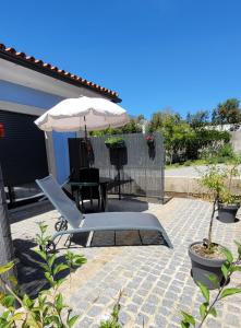 a patio with a table and an umbrella and a chair at Jardim das Oliveiras - Suítes com Vista in Ponte de Lima