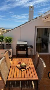 a wooden table and chairs on a balcony with a table and a grill at BANUS HAUSE Marbella in Marbella