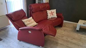 einen roten Lehnstuhl und einen Stuhl im Wohnzimmer in der Unterkunft Ferienhaus Bungalow SixtyTwo, für 2 Personen in der Rhönresidence Dipperz-Friesenhausen in Dipperz