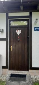 eine braune Tür mit einem Herzschild drauf in der Unterkunft Ferienhaus Bungalow SixtyTwo, für 2 Personen in der Rhönresidence Dipperz-Friesenhausen in Dipperz