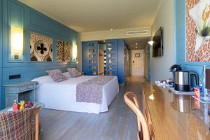 1 dormitorio con paredes azules y 1 cama con mesa en Adrián Hoteles Colón Guanahaní Adultos Only en Adeje