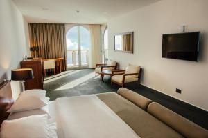 a hotel room with a bed and a flat screen tv at Avala Resort & Villas in Budva
