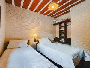 duas camas num quarto com uma parede de tijolos em Toca em Petrópolis