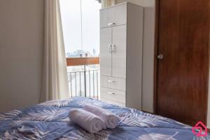 a bed with towels on top of it with a window at Departamento con vista en San Borja in Lima