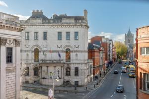 Dublin Castle Suites في دبلن: مبنى قديم على شارع المدينة وبه سيارات