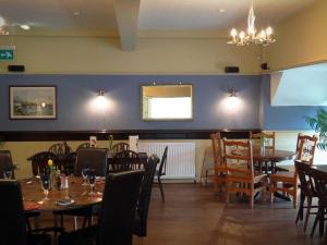 a dining room with tables and chairs and a chandelier at Anchor Hotel in Haydon Bridge