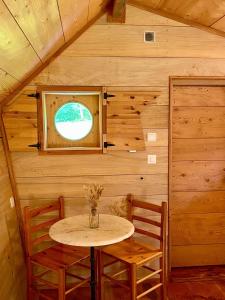 Lac des Rouges TruitesCamping-Chalets La Favière的带窗户的小屋里的一张小桌子和几把椅子
