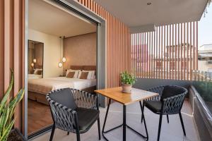アテネにあるThe Residence Christokopidou Hotel & Spaのベッド、テーブル、椅子が備わるホテルルームです。