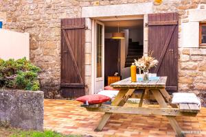 uma mesa de piquenique em frente a um edifício de tijolos em RÉF 302 - LARMOR-PLAGE longère 3 pièces avec terrasse et jardin proche mer et commodités em Larmor-Plage