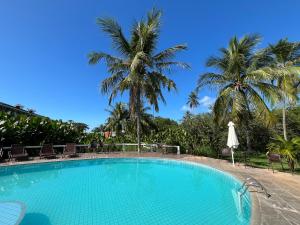a swimming pool with palm trees in the background at Apto/Hotel Praia Taperapuã - Beira Mar in Porto Seguro