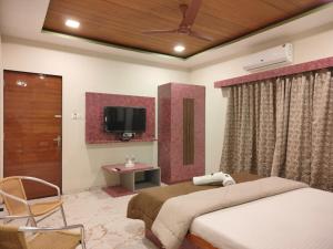a bedroom with a bed and a tv on the wall at Woodland farm vila in Mahabaleshwar