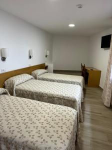 een kamer met drie bedden in een kamer met een tv bij Hostal cazalegas in Cazalegas