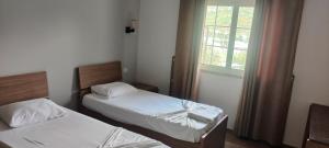 two beds in a small room with a window at Hotel VEAL in Tepelenë