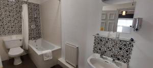 a bathroom with a toilet and a tub and a sink at Best Western Hotel Hatfield in Lowestoft