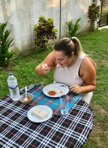 una mujer sentada en una mesa de picnic comiendo comida en Lucky's Homestay en Maho