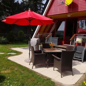 a table and chairs with a red umbrella on a patio at Eifeler Finnhaus mit Sauna Haus in Dockweiler