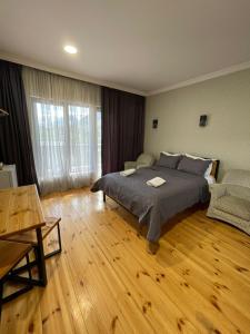 a bedroom with a large bed and a wooden floor at Bibo's Kokhi Guesthouse in Stepantsminda