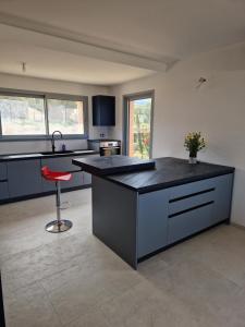 a kitchen with a black counter and a red stool at L'Osari, villa vue mer, accès plage à pied, golf, jardin clos pour enfants in Palasca +24 photos