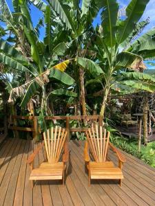 2 sillas sentadas en una terraza de madera con palmeras en Pousada Banana Verde, en Ilhabela