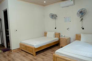 a bedroom with two beds and a fan at Tran Chau Garden Home in Cat Ba