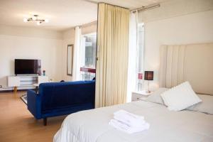 1 dormitorio con 1 cama y 1 silla azul en Departamento con vista de Lima en San Borja en Lima