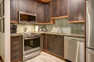 a kitchen with wooden cabinets and stainless steel appliances at Tremblant Prestige - Étoile 1520-2 in Mont-Tremblant