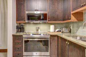 a kitchen with wooden cabinets and a stainless steel oven at Tremblant Prestige - Étoile 1520-2 in Mont-Tremblant