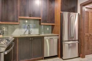 a kitchen with wooden cabinets and a stainless steel refrigerator at Tremblant Prestige - Étoile 1520-2 in Mont-Tremblant