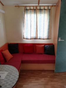 a red couch in a room with a window at CAMPING 3* ! PROGHE DES GORGES DU VERDON ET LAC DE STE CROIX 04500 ! TOUT EQUIPE ! CHAMPS DE LAVANDES ! CALME ! NBRES ACTIVITES ! RANDONNEES ! NAUTISME ! in Sainte-Croix-de-Verdon