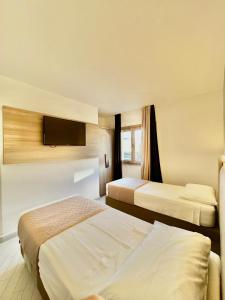 a hotel room with two beds and a flat screen tv at Suite con giardino in La Maddalena