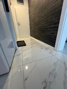 a hallway with white marble floors and a brick wall at Apartman City Center 2 in Prijedor