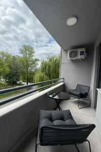 Un balcón con una silla, una mesa y una ventana en Apartman City Center 2, en Prijedor