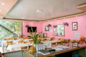 a restaurant with pink walls and tables and chairs at Tran Chau Garden Home in Cat Ba