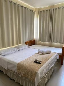 a bedroom with two beds with white sheets and curtains at Hotel Italia Beach in Fortaleza