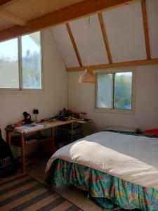 Un dormitorio con una cama, un escritorio y ventanas. en Eco house on the mountain, en Yavneʼel