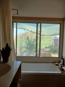 ventana en el baño con vistas al campo en Eco house on the mountain, en Yavneʼel