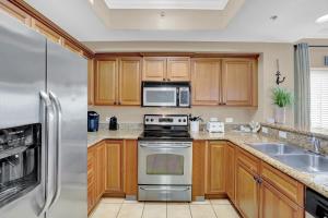 a kitchen with wooden cabinets and stainless steel appliances at Seawind By Liquid Life in Gulf Shores