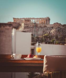 uma mesa com um copo de vinho e um prato de comida em The Residence Christokopidou Hotel & Spa em Atenas