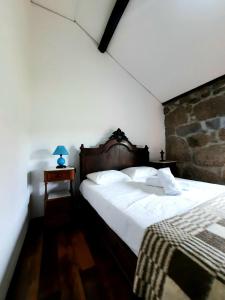 Casa do Tarrão : غرفة نوم بسرير ابيض كبير وبجدار حجري