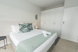 1 dormitorio con 1 cama blanca y armario blanco en The High Flyer, en Gqeberha