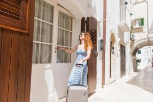 uma mulher num vestido com uma mala numa rua em La Perla Del Mare em Monopoli