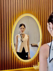 a woman standing in front of a mirror at Marina Hotel Ha Noi in Hanoi