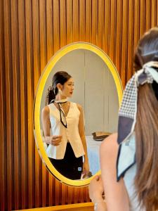 a woman looking at her reflection in a mirror at Marina Hotel Ha Noi in Hanoi