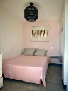 1 dormitorio con 1 cama con sábanas rosas y 2 cuadros en la pared en [Vue Mer] Beau 2pièces, proche plage, centre-ville, en Cannes