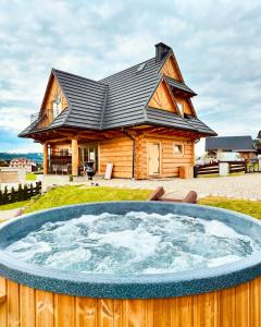 a log cabin with a hot tub in front of a house at Farmerska Chata in Czarna Góra
