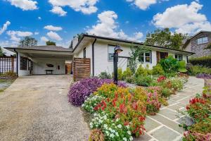 a house with a bunch of flowers in front of it at Poolside Bungalow with Fire Pit Fun and King Suite in Charlotte